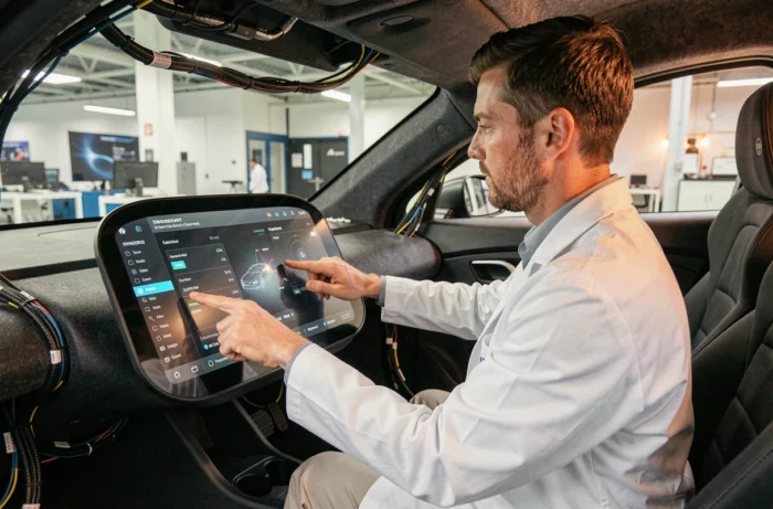 Ingénieur automobile analysant un tableau de bord numérique dans l'habitacle d'un prototype de véhicule électrique